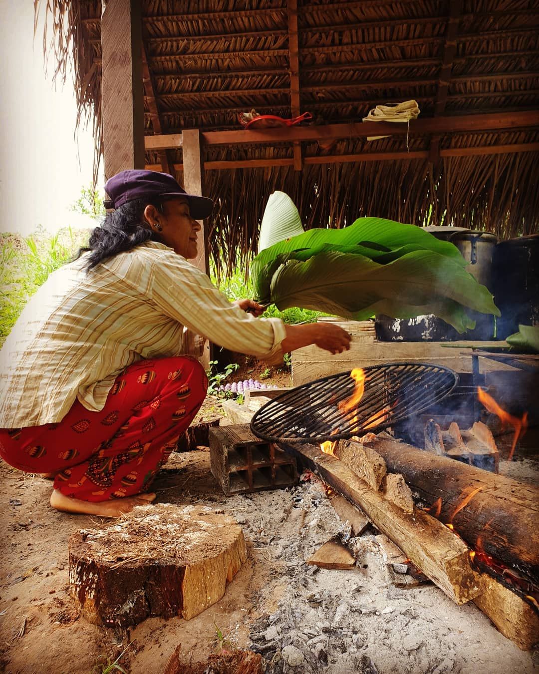 Woman cooking at fire, face not clear, tiny, at Ampiri.