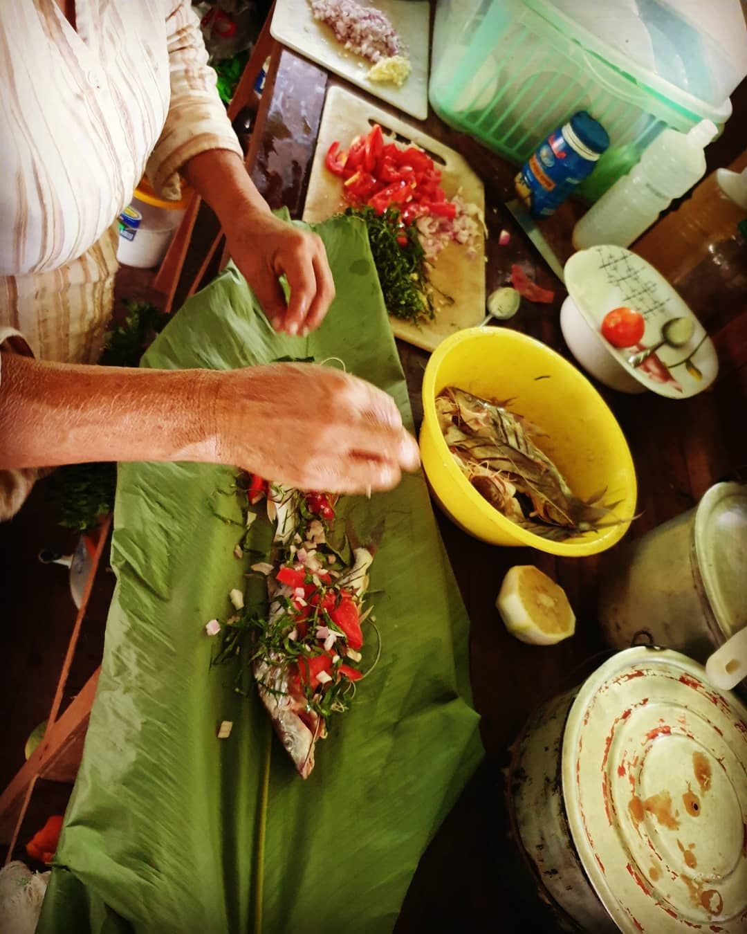 Hands over leaf-wrapped food, at Ampiri.