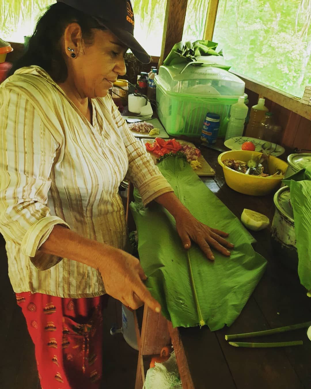 Woman preparing leaf wraps, face down, at Ampiri.